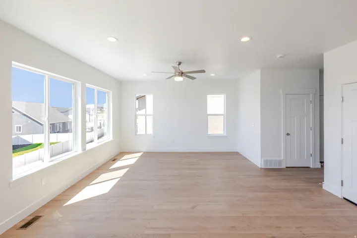 Recessed ceiling lighting, wood-finish flooring, multiple windows, ceiling fan with light, and white interior doors