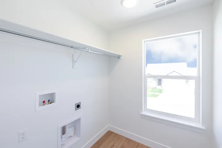 Laundry area featuring wood-finish flooring, a single window, and a built-in hanging rod