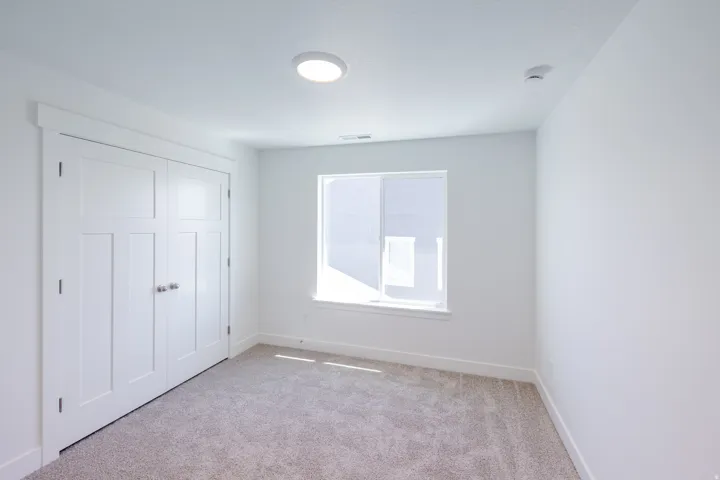 Recessed lighting, white walls, light-toned carpet, white trim, and a window with white casing
