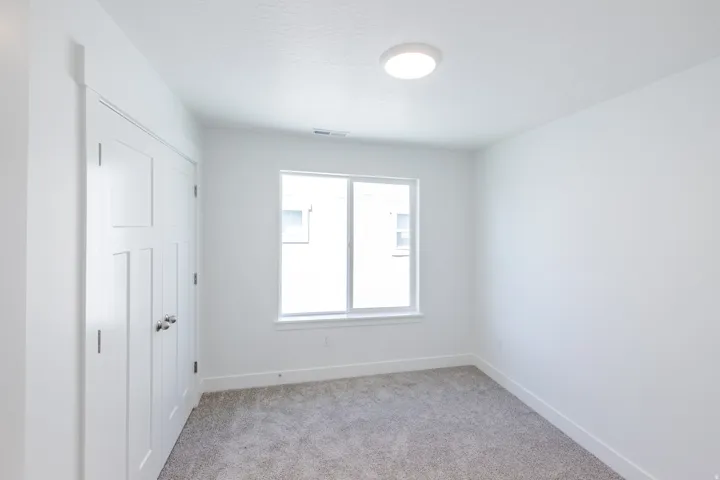 White walls, gray carpeting, dual-pane window, and a flush-mount ceiling light