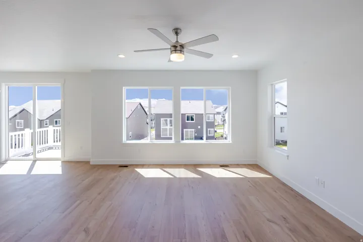 Expansive room featuring wood-finish flooring, a contemporary ceiling fan, recessed lighting, a sliding glass door opening to a deck, and multiple windows