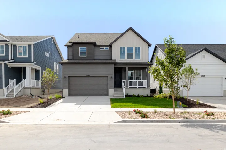 Contemporary two-story residence featuring gray siding with white board and batten accents, a covered front porch with white railing, and a two-car garage