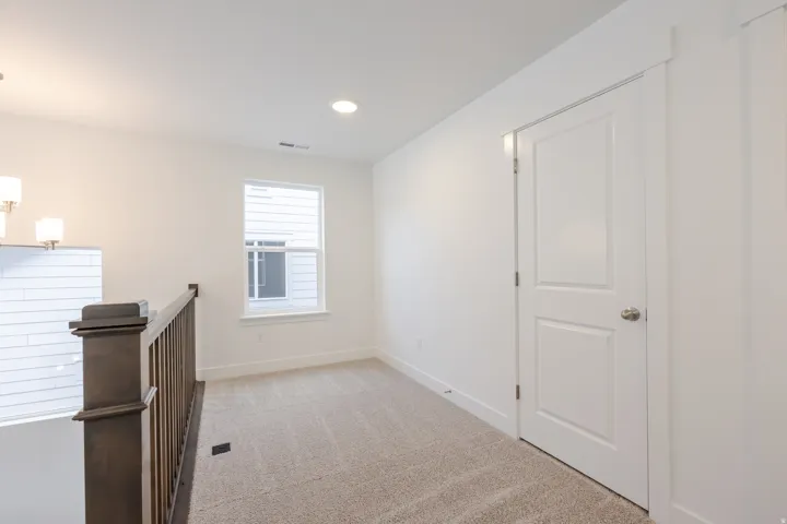 Second-story landing featuring a window with white trim, recessed ceiling lighting, and neutral carpeting
