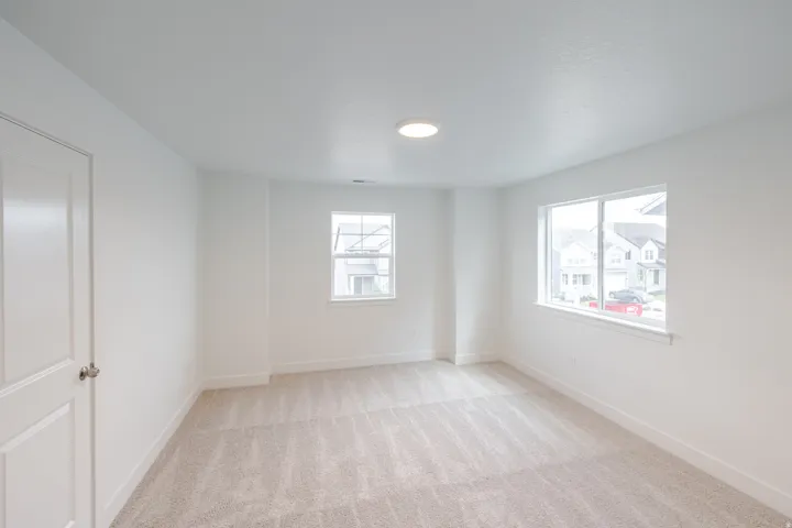 Carpeted room with white walls, baseboards, and trim