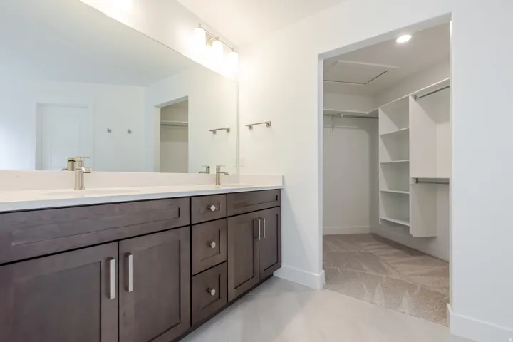 Bathroom featuring a dual vanity with dark wood-finish cabinetry, light countertops, and a large mirror with overhead lighting