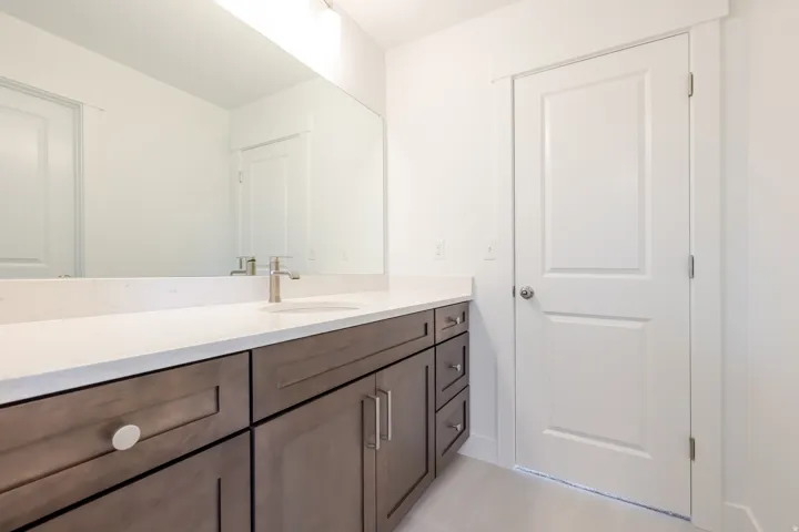 Bathroom vanity featuring a quartz countertop with an undermount sink and brushed nickel faucet