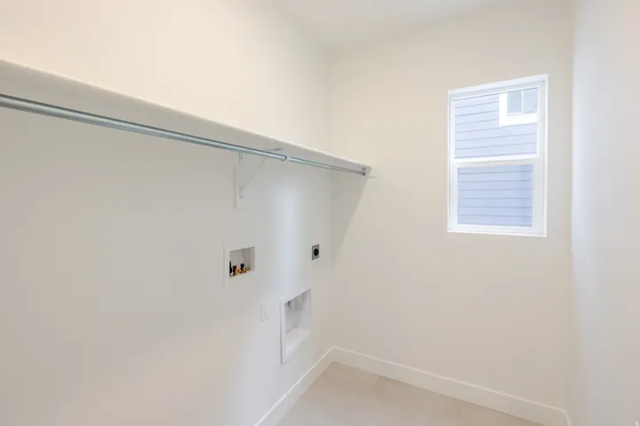 Utility room featuring a window, wood-finish flooring, a white shelf, a clothing rod, and laundry hookups