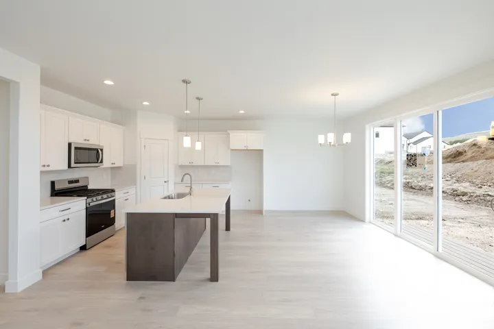 Contemporary kitchen featuring an island with a stainless steel sink, white cabinetry, integrated stainless steel appliances, and wood-finish flooring