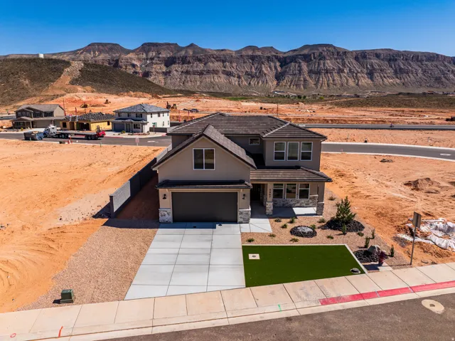 View of front of house featuring a mountain view, stone siding, concrete driveway, stucco siding, and an attached garage