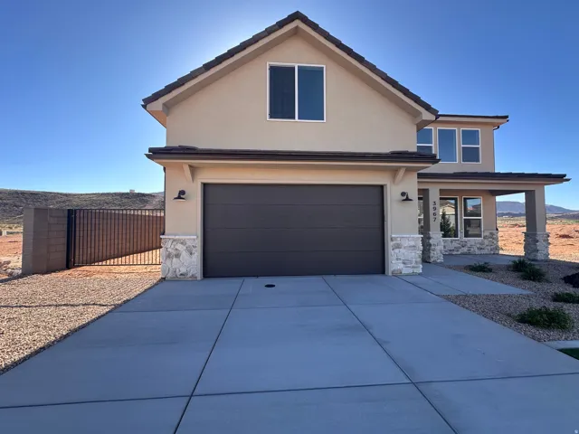 View of front facade featuring stone siding, stucco siding, concrete driveway, an attached garage, and covered porch