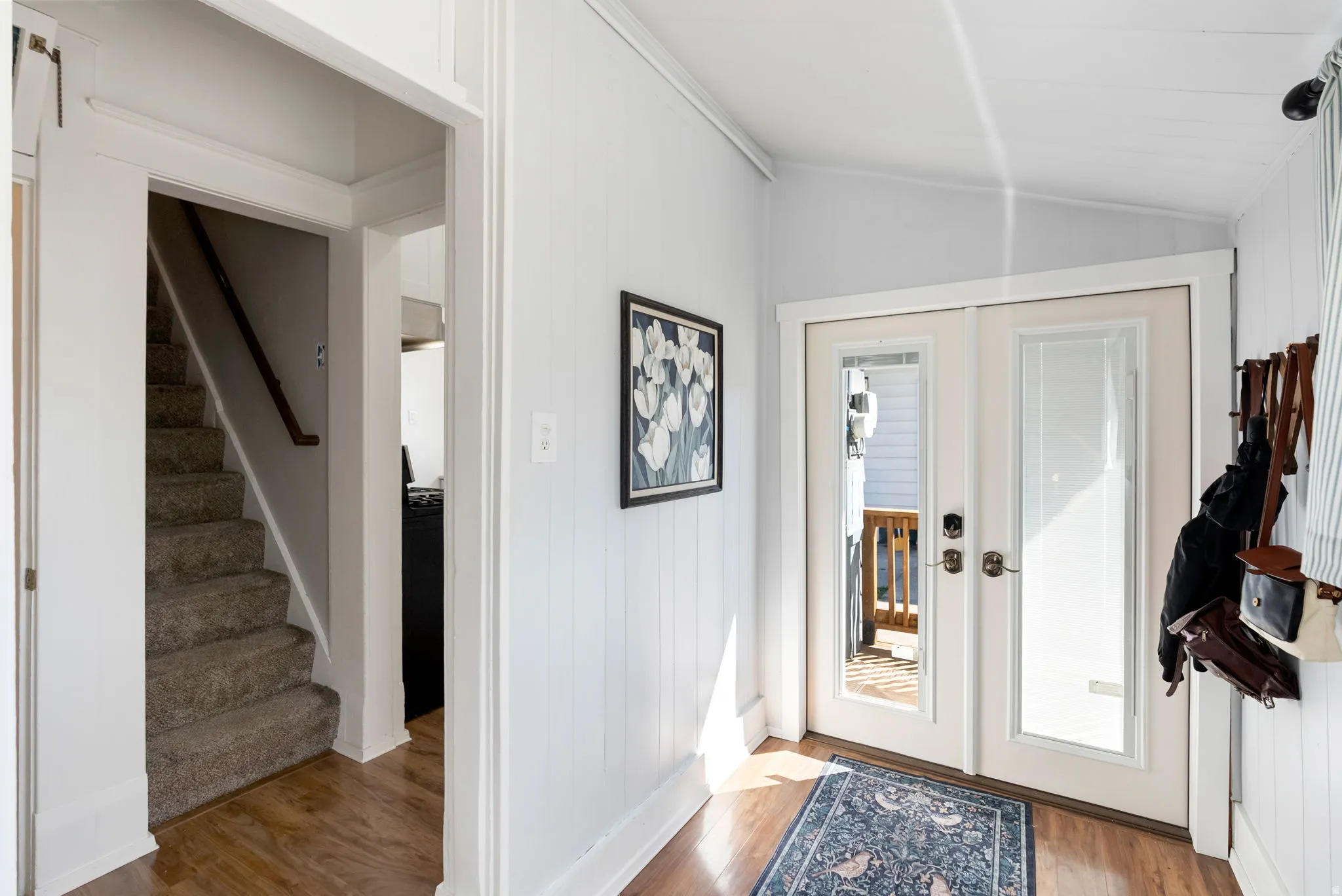 Foyer featuring french doors, light wood-style floors, and lofted ceiling