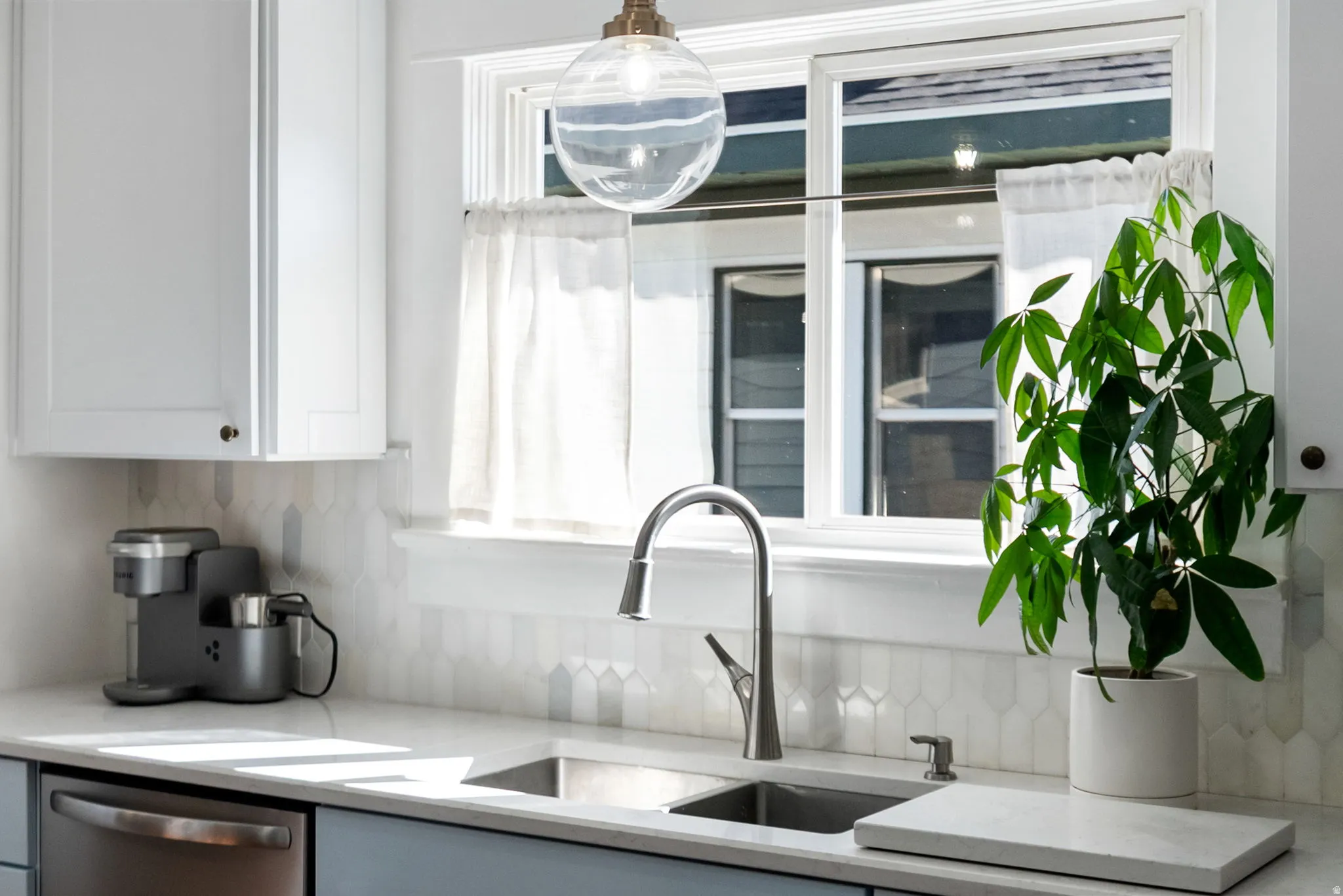 Kitchen with light stone countertops, stainless steel dishwasher, white cabinets, and decorative backsplash