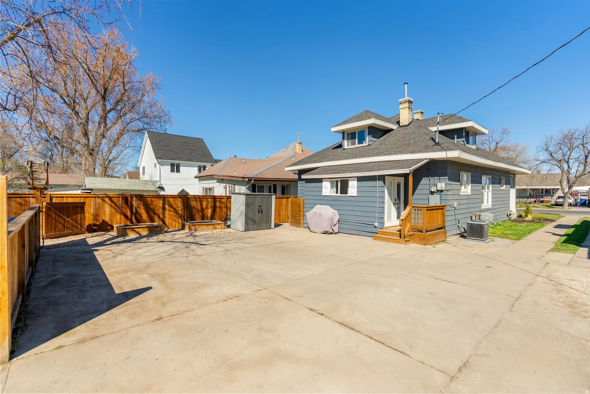 Rear view of house featuring a chimney, roof with shingles, and a fenced backyard