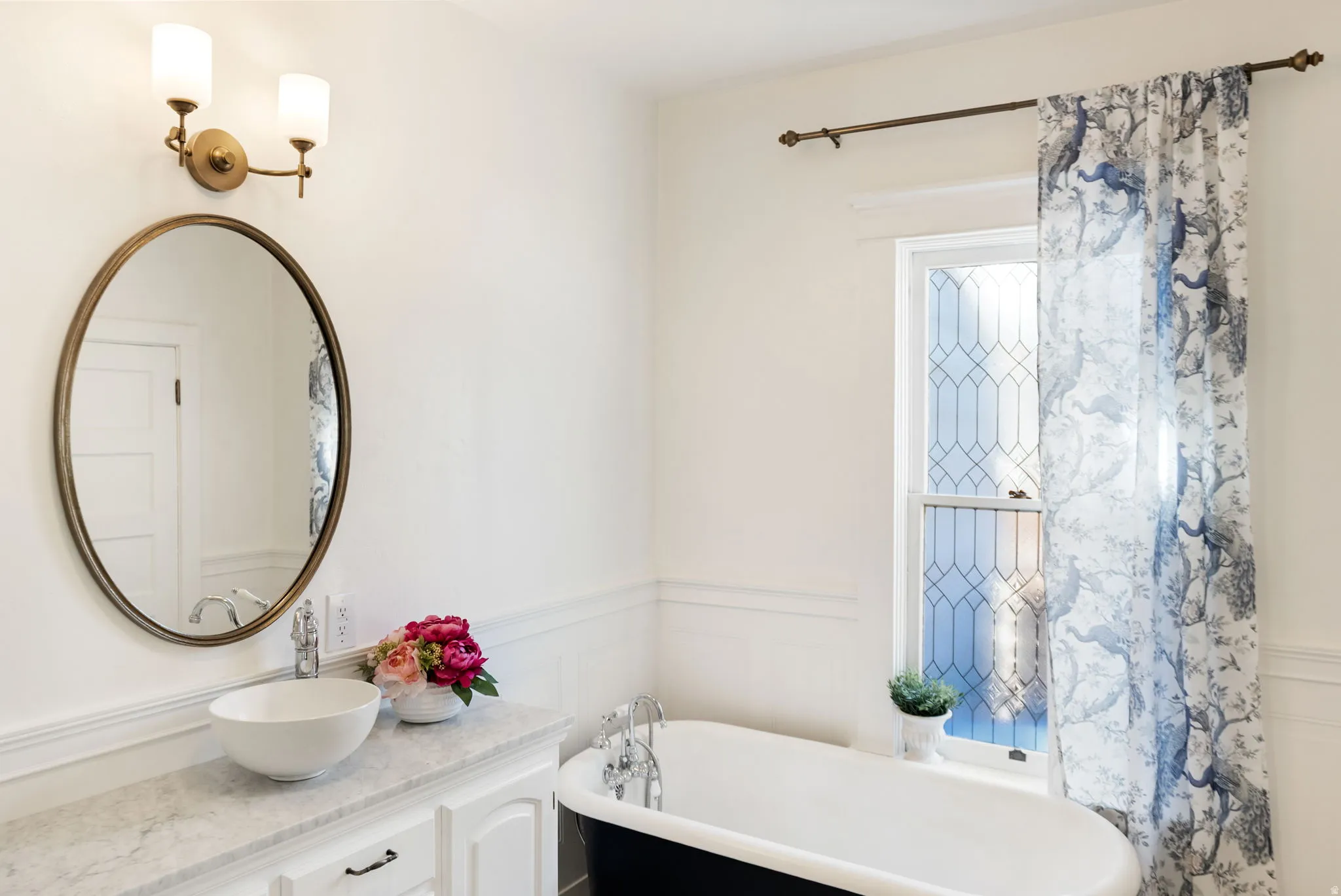 Full bath featuring a freestanding tub, vanity, a wainscoted wall, and a decorative wall