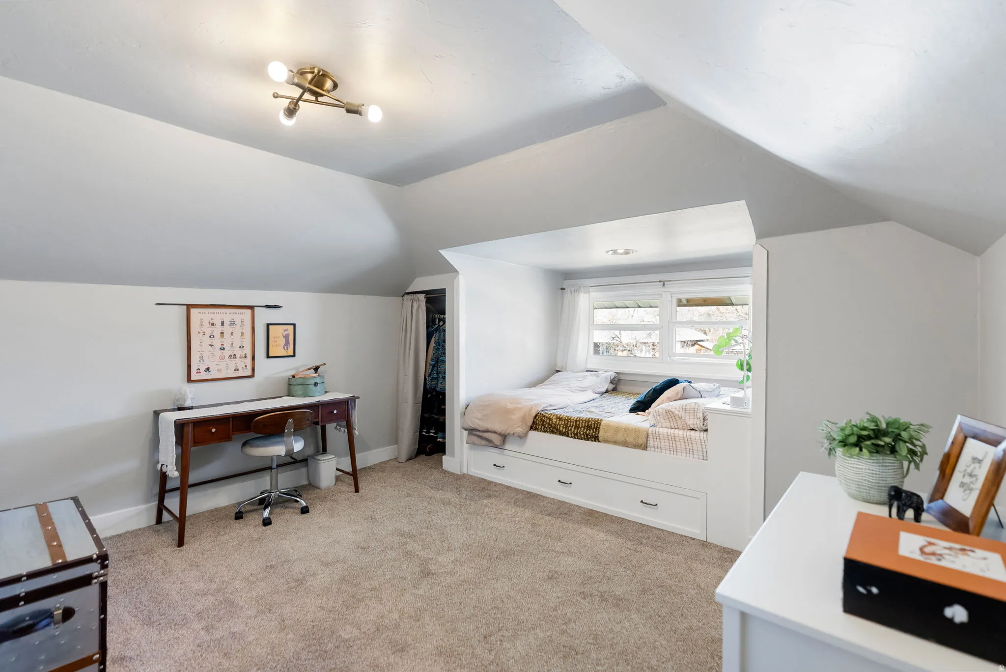 Bedroom with light carpet, a desk, lofted ceiling, and a closet