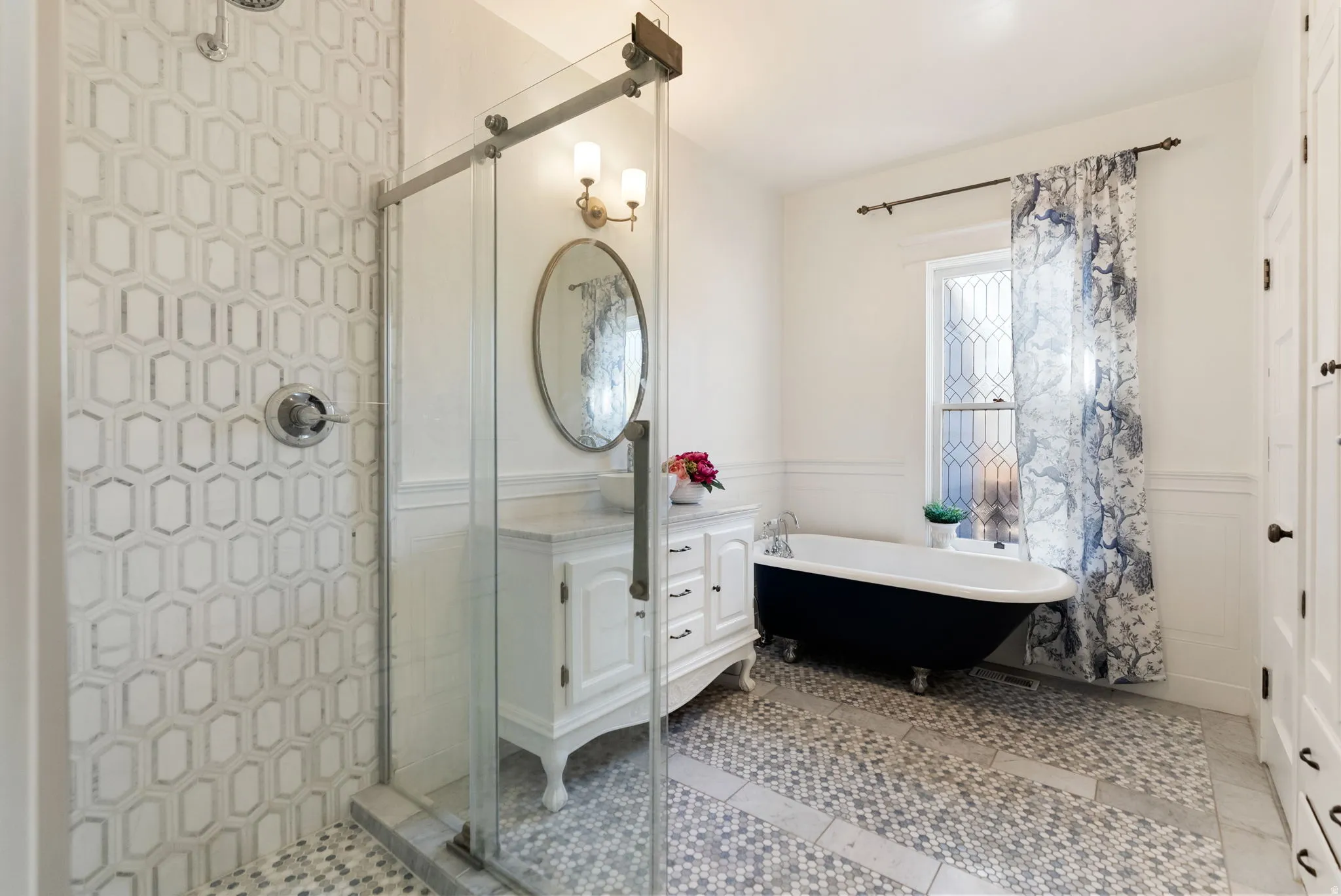 Full bath featuring a wainscoted wall, vanity, a freestanding tub, a shower stall, and light tile patterned flooring