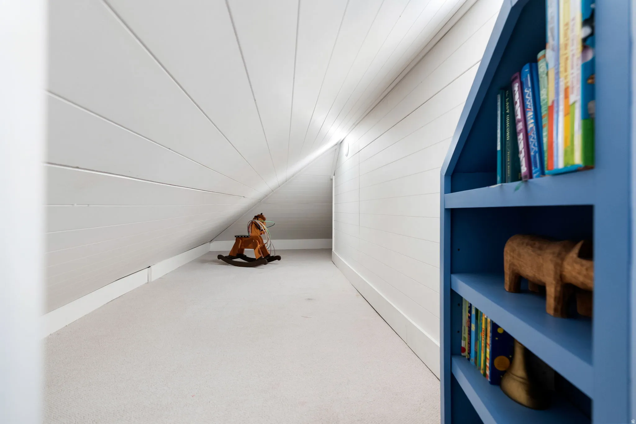 Bonus room with carpet floors, wooden walls, and vaulted ceiling