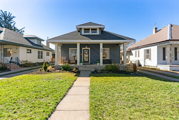 Bungalow with covered porch, a front lawn, and a shingled roof