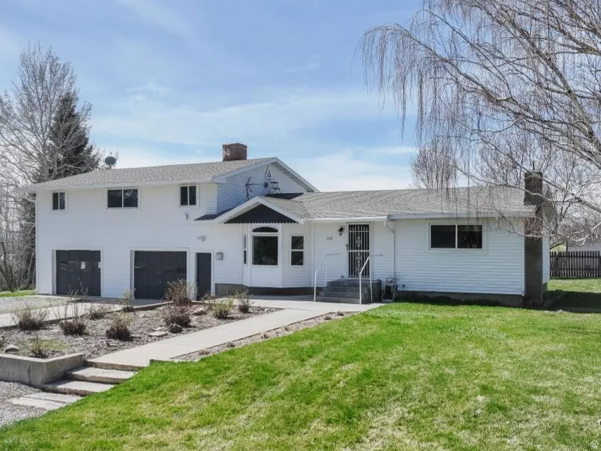 Back of house with a chimney, a garage, and driveway
