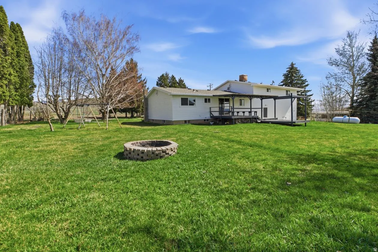 Rear view of house with a deck, a chimney, and an outdoor fire pit