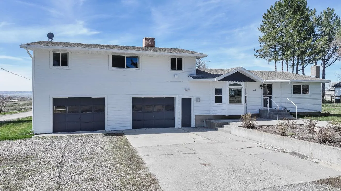 View of front of property with a chimney, driveway, and a garage