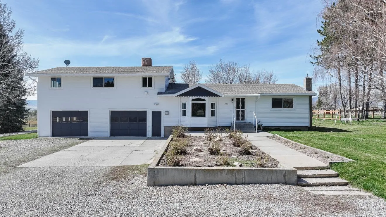 View of front of property with a chimney, concrete driveway, an attached garage, a front lawn, and a shingled roof