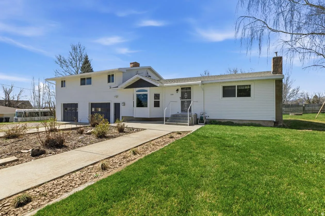 View of front of property with a chimney, an attached garage, and driveway