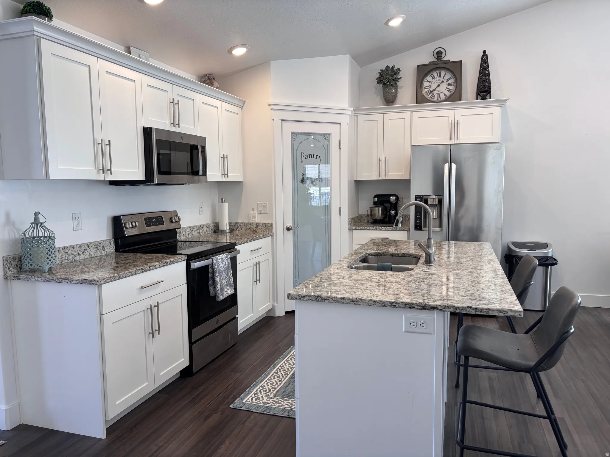 Well-designed kitchen with an oversized island, granite countertops, stainless steel appliances, and convenient pantry storage.