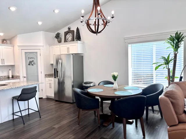 Dining area with vaulted ceiling, dark wood-type flooring, and beautiful hanging light.
