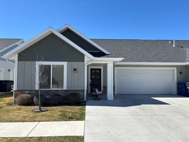 Inviting front exterior showcasing stylish board and batten siding, attached garage, and ample driveway space.
