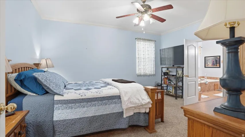 Bedroom featuring light carpet, crown molding, and ceiling fan