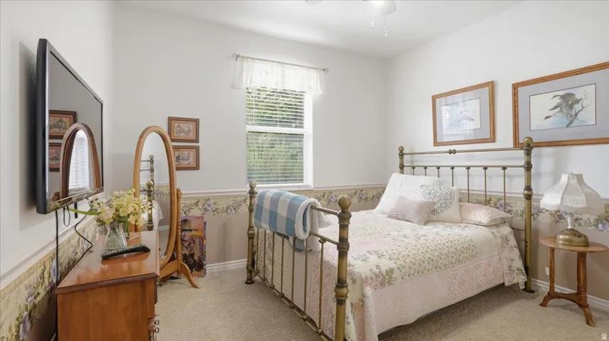 Bedroom with ceiling fan and light colored carpet