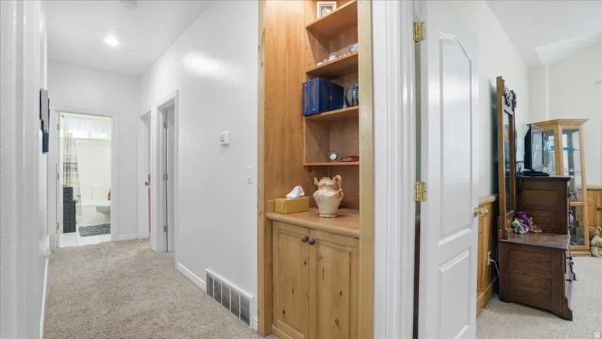 Corridor featuring light carpet and baseboards
