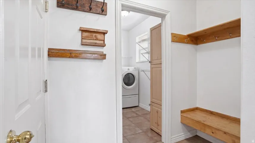 Laundry area with washer / clothes dryer and light tile patterned floors