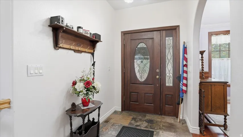 Foyer entrance with dark stone finish flooring, arched walkways, and ornamental molding