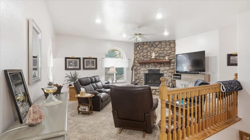 Carpeted living room with a fireplace and a ceiling fan