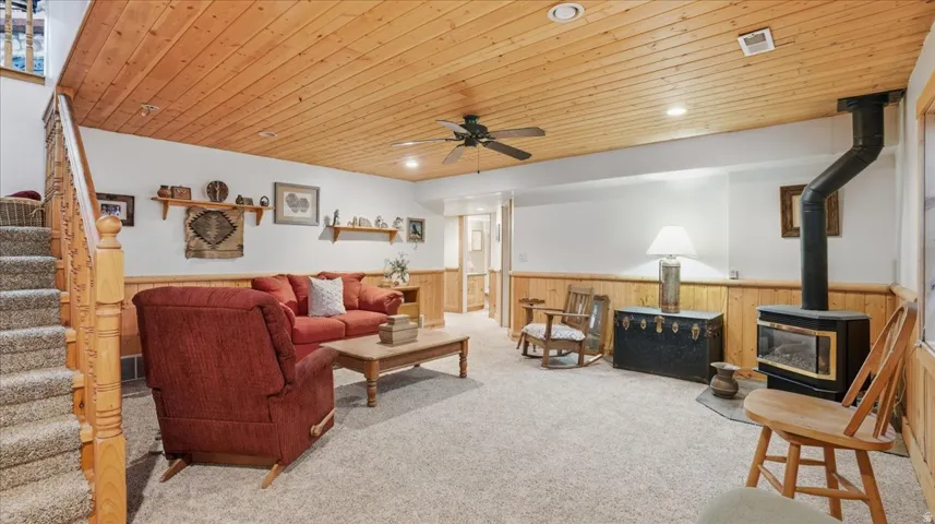 Living room with wooden ceiling, recessed lighting, carpet, a ceiling fan, and a wainscoted wall