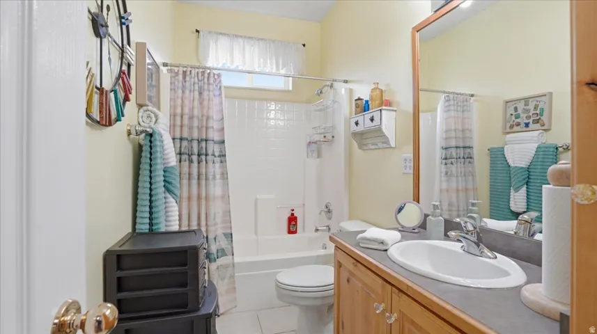 Bathroom featuring vanity, shower / bathtub combination with curtain, and light tile patterned flooring