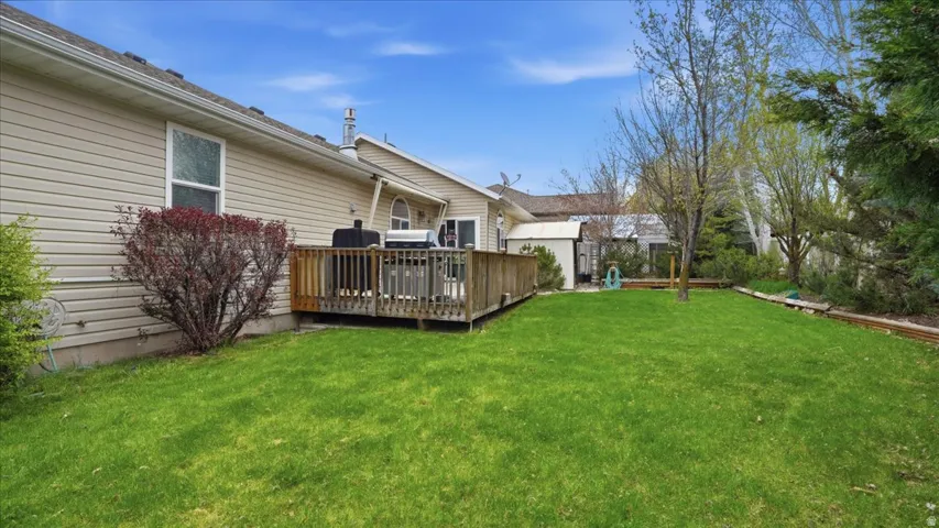 View of grassy yard with a wooden deck