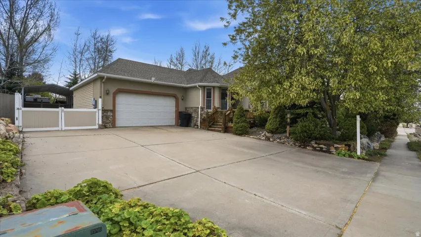 View of front of property featuring an attached garage, stucco siding, concrete driveway, stone siding, and roof with shingles