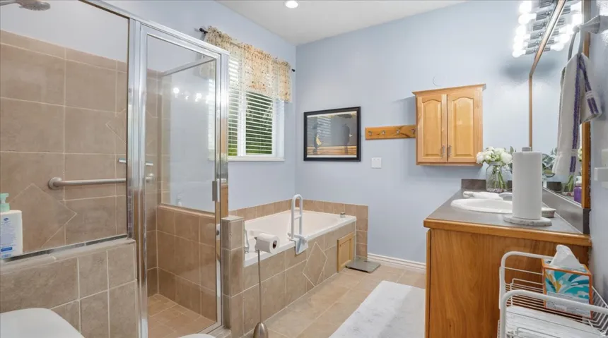 Full bath with a bath, vanity, a stall shower, and light tile patterned flooring