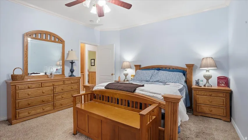 Bedroom featuring light colored carpet, a ceiling fan, and crown molding