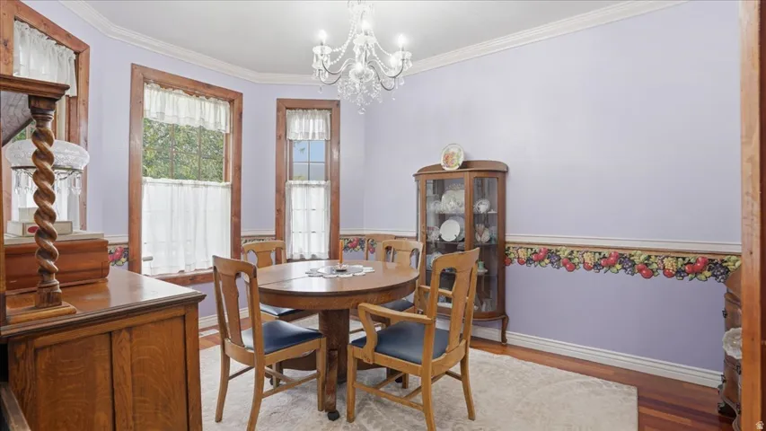 Dining area featuring wood finished floors, ornamental molding, and suspended lighting