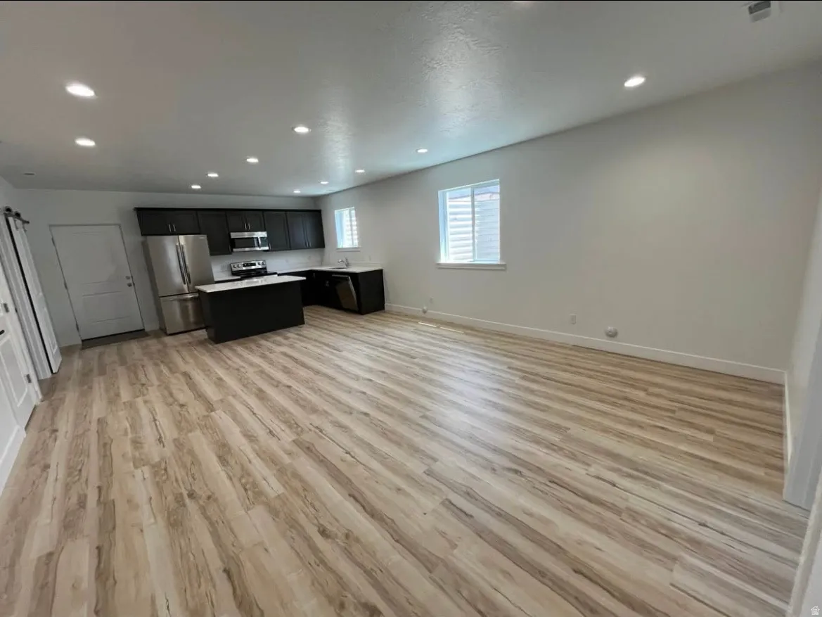 Kitchen featuring open floor plan, light countertops, dark cabinetry, stainless steel appliances, and recessed lighting