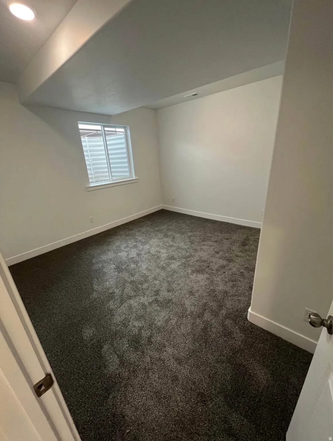 Empty room with dark colored carpet and baseboards