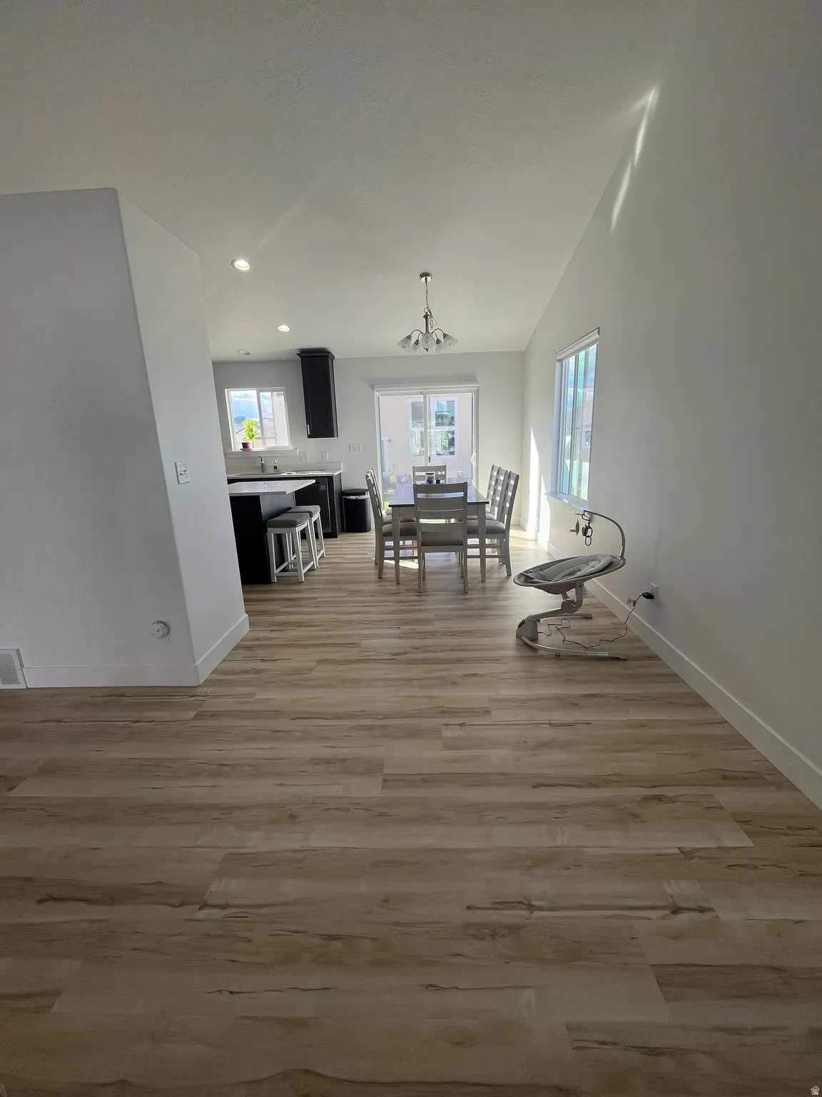 Dining room featuring light wood-style floors, vaulted ceiling, and suspended lighting