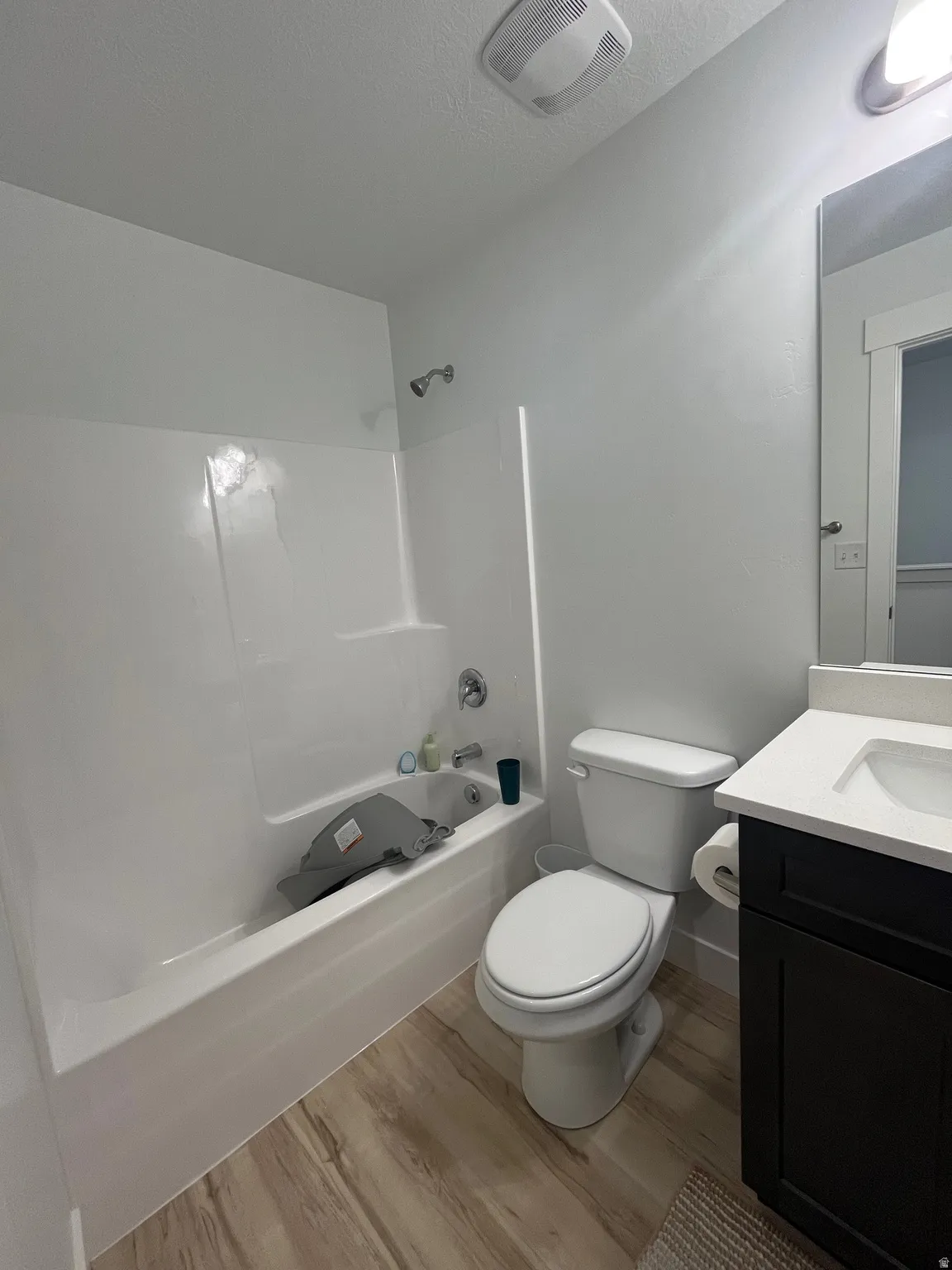 Bathroom with vanity, light wood-style floors, shower / bath combination, and a textured ceiling