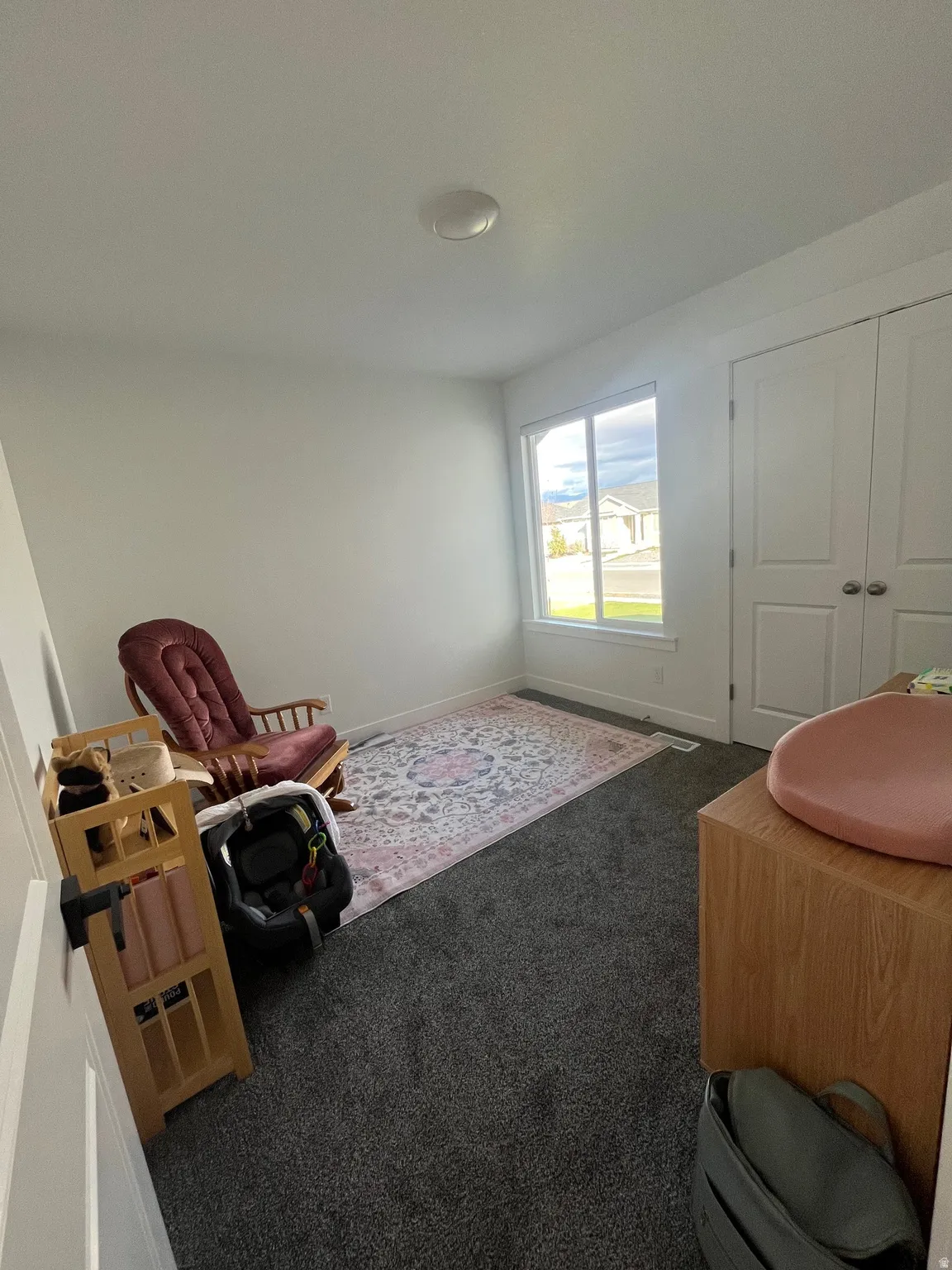 Living area featuring dark colored carpet and baseboards