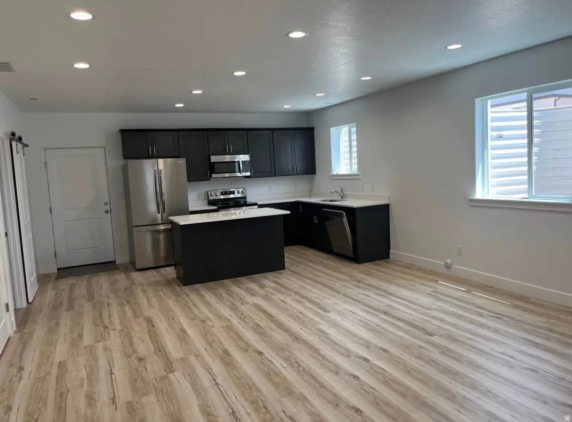 Kitchen with light countertops, stainless steel appliances, a center island, light wood-style flooring, and recessed lighting