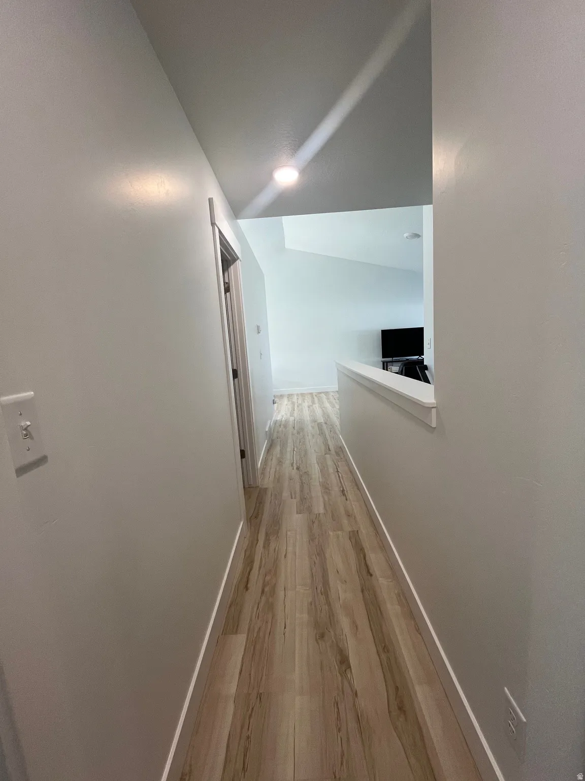 Hallway featuring light wood finished floors and baseboards